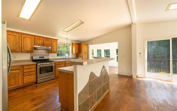 a kitchen with stainless steel appliances granite countertop a stove top oven a sink dishwasher a refrigerator and a microwave oven with wooden floor