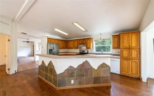 a living room with stainless steel appliances granite countertop furniture wooden floor and a large window