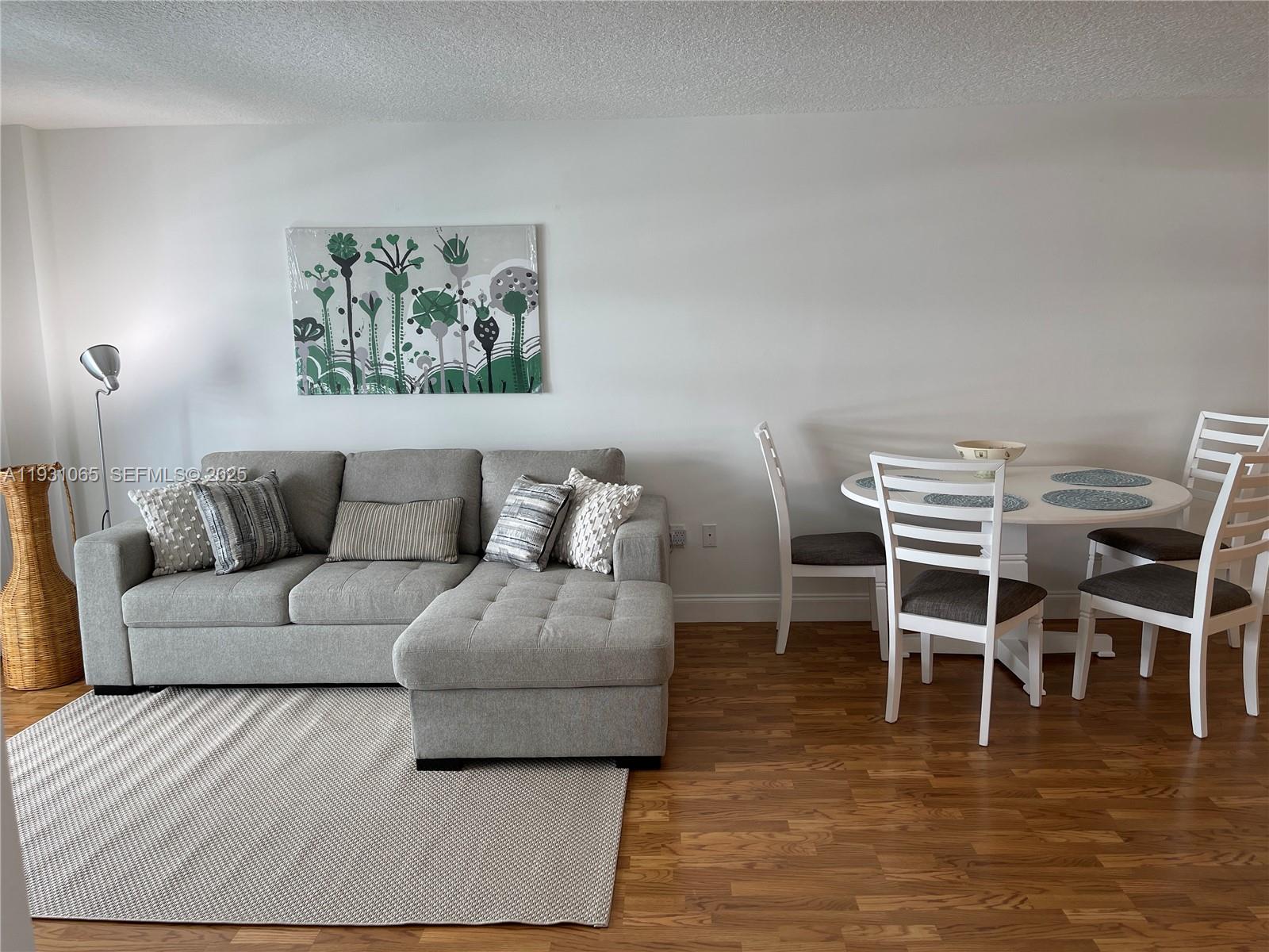 6917 Collins Avenue, Unit 1008 Miami Beach, FL 33141 - Photo 39 of 64 a living room with furniture a wooden floor and a dining table