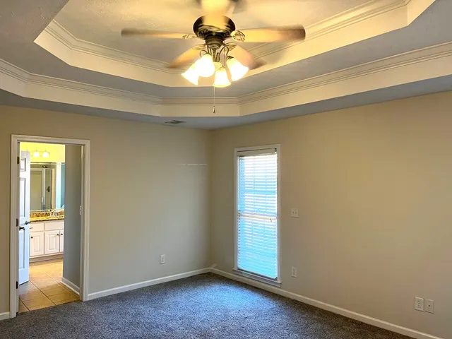 an empty room with a chandelier fan and windows