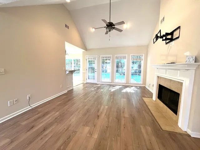 a view of an empty room with wooden floor fireplace and a window