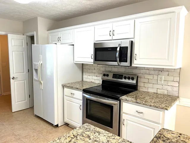 a kitchen with granite countertop a stove microwave and refrigerator