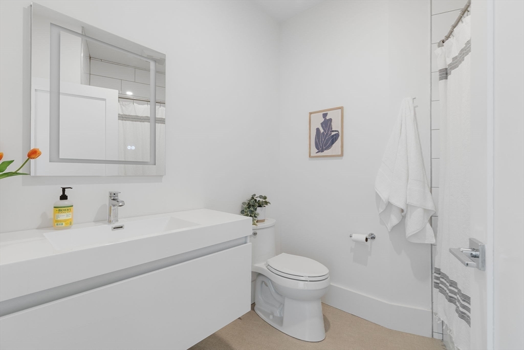 65 Pleasant Street, Unit 3 Brookline, MA 02446 - Photo 8 of 19 a bathroom with a sink mirror vanity and toilet