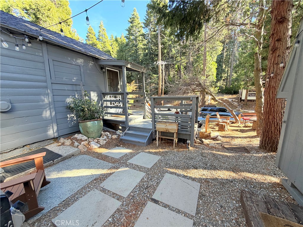 926 Kuffel Canyon Road Lake Arrowhead, CA 92385 - Photo 16 of 52 a view of a patio with table and chairs potted plants and a large tree