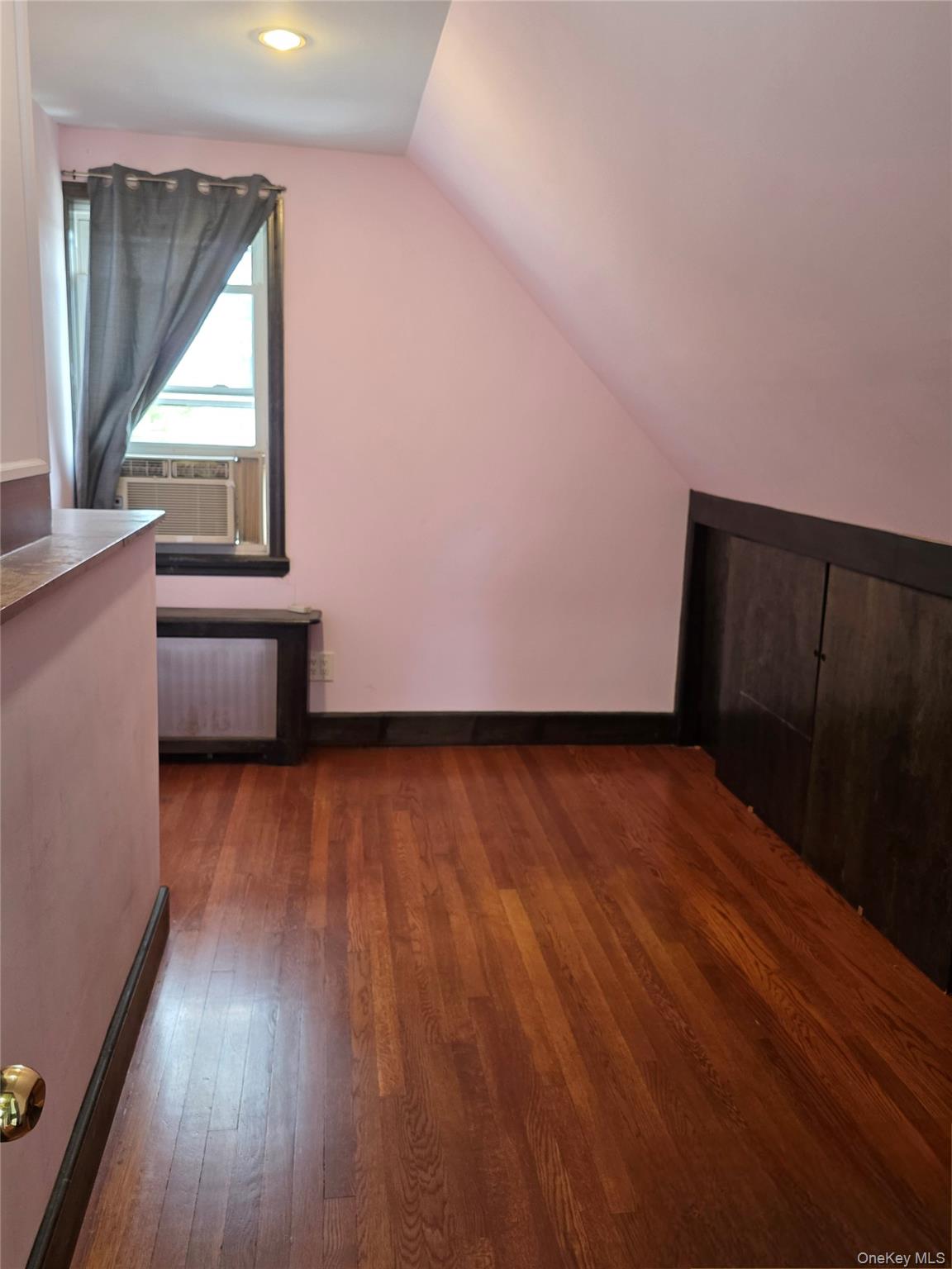 65-26 167th Street Queens, NY 11365 - Photo 12 of 15 Additional living space featuring vaulted ceiling, a baseboard radiator, dark wood-style floors, radiator heating unit, and cooling unit