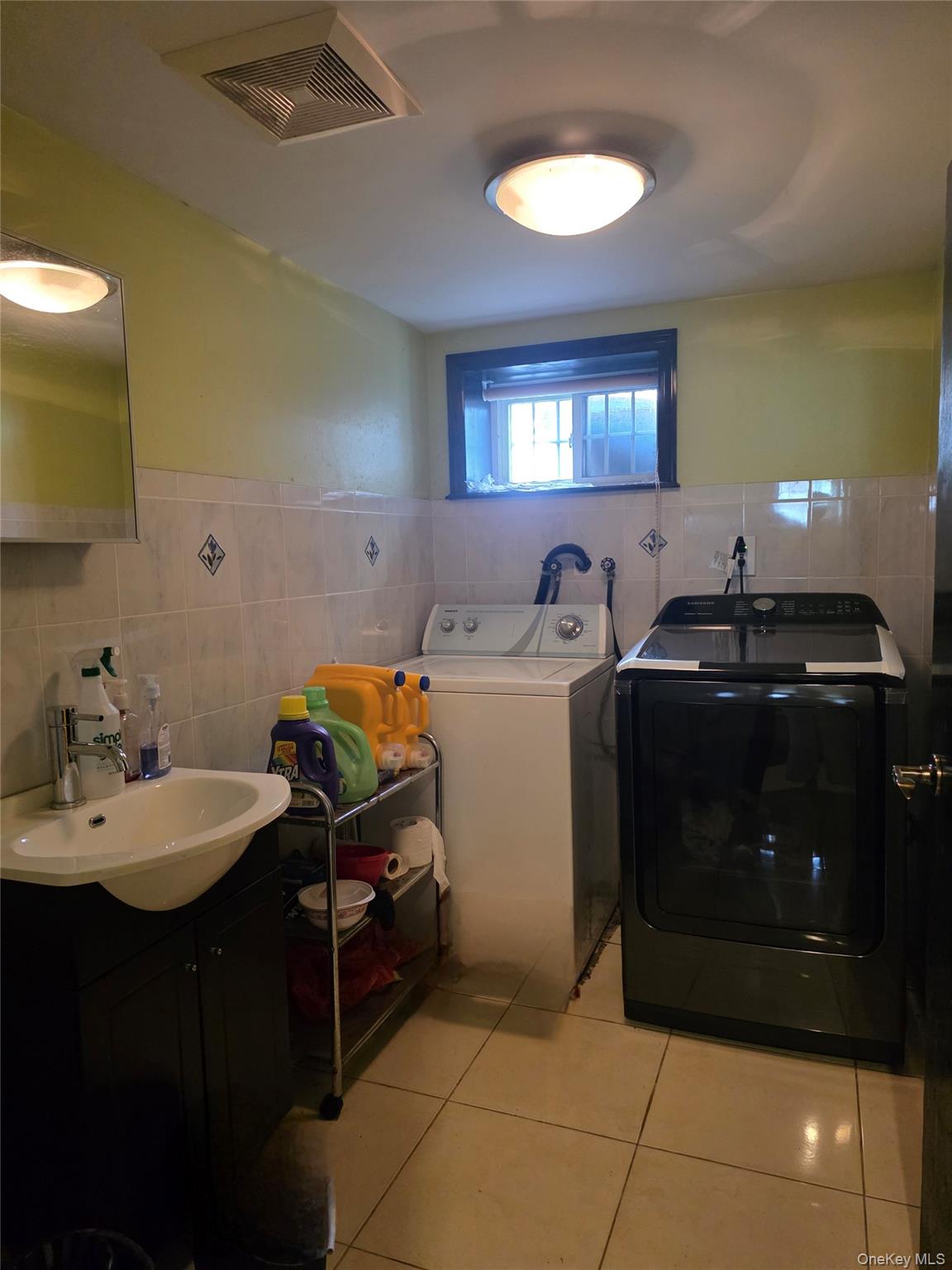 65-26 167th Street Queens, NY 11365 - Photo 14 of 15 Laundry area with tile walls, light tile patterned floors, independent washer and dryer, and wainscoting