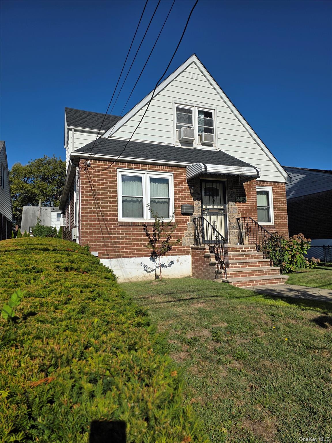 65-26 167th Street Queens, NY 11365 - Photo 3 of 15 View of front of home featuring roof with shingles, brick siding, and a front lawn