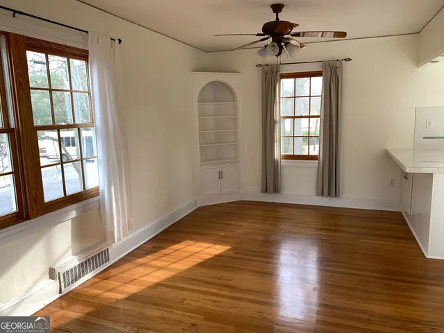 a view of empty room with wooden floor and fan