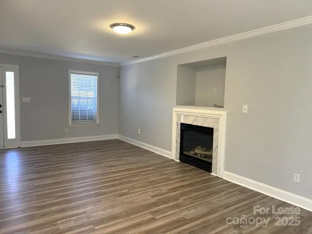 an empty room with wooden floor fireplace and windows