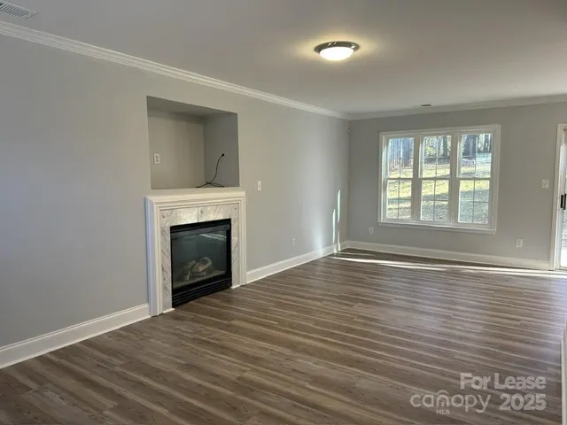an empty room with wooden floor fireplace and windows