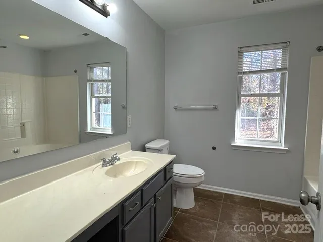 a bathroom with a sink toilet a mirror and a window