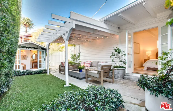 a view of a patio with table and chairs potted plants and a large tree