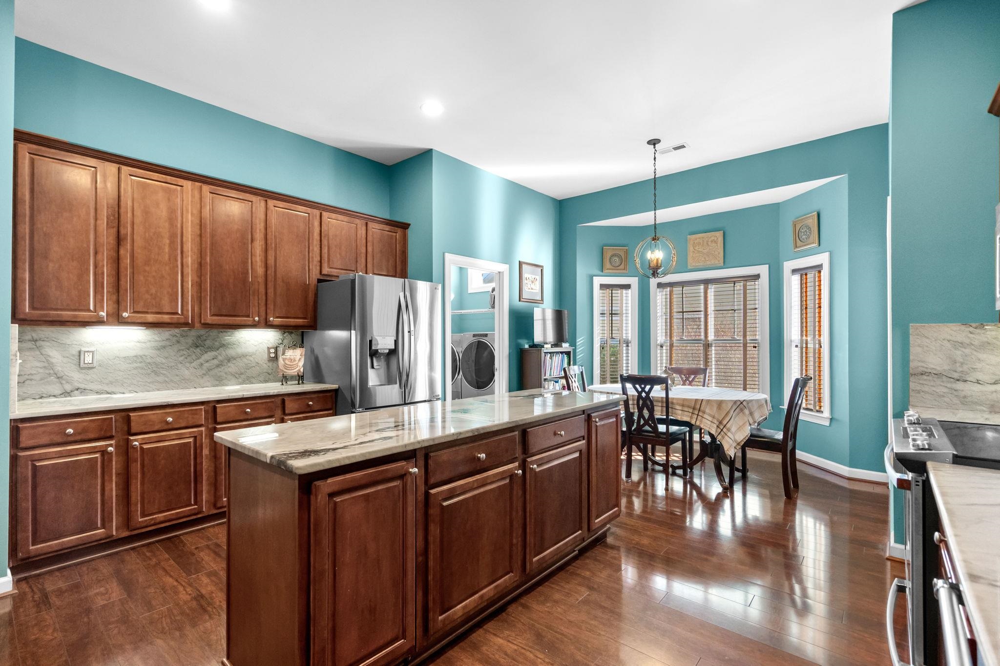 699 Bullrush Court Calabash, NC 28467 - Photo 13 of 40 Kitchen with appliances with stainless steel finishes, decorative backsplash, pendant lighting, a kitchen island, and light stone counters