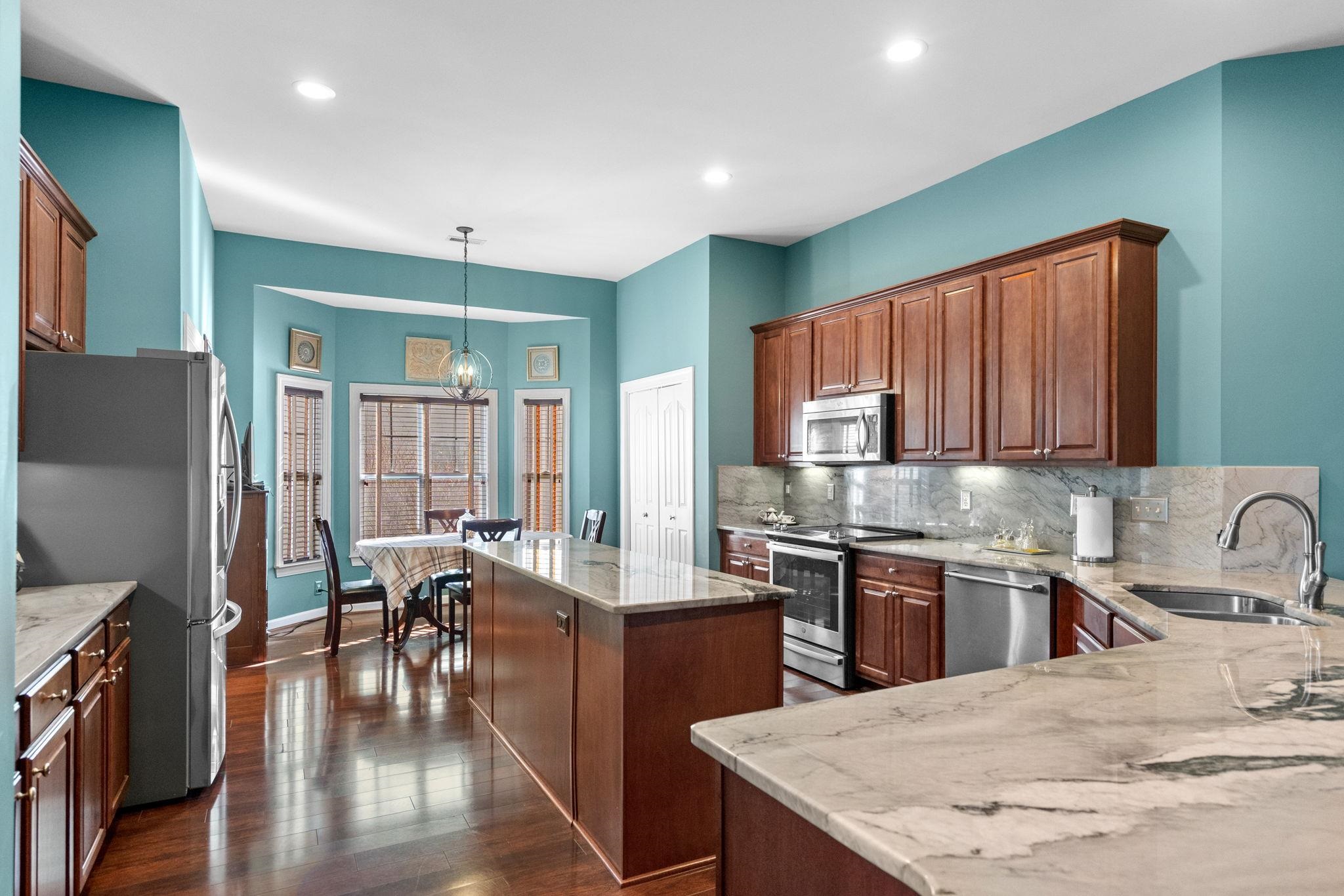 699 Bullrush Court Calabash, NC 28467 - Photo 14 of 40 Kitchen with a kitchen island, appliances with stainless steel finishes, hanging light fixtures, light stone counters, and recessed lighting
