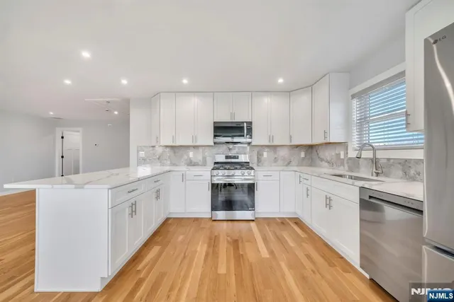 a large kitchen with cabinets stainless steel appliances a sink and a stove