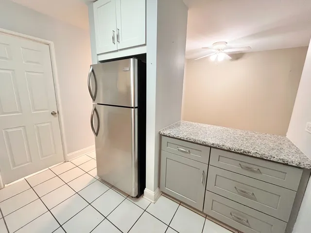 a view of cabinets with refrigerator and white cabinets