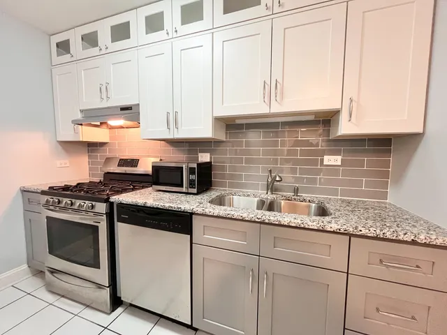 a kitchen with stainless steel appliances granite countertop white cabinets and a stove a sink