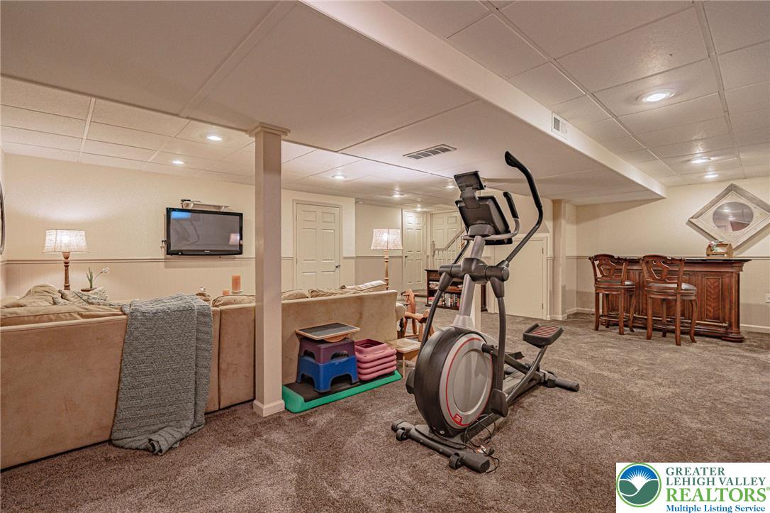 4542 Springfield Drive Coplay, PA 18037 - Photo 59 of 89 A versatile finished basement offers a comfortable family room alongside a dedicated exercise space and a dry bar.