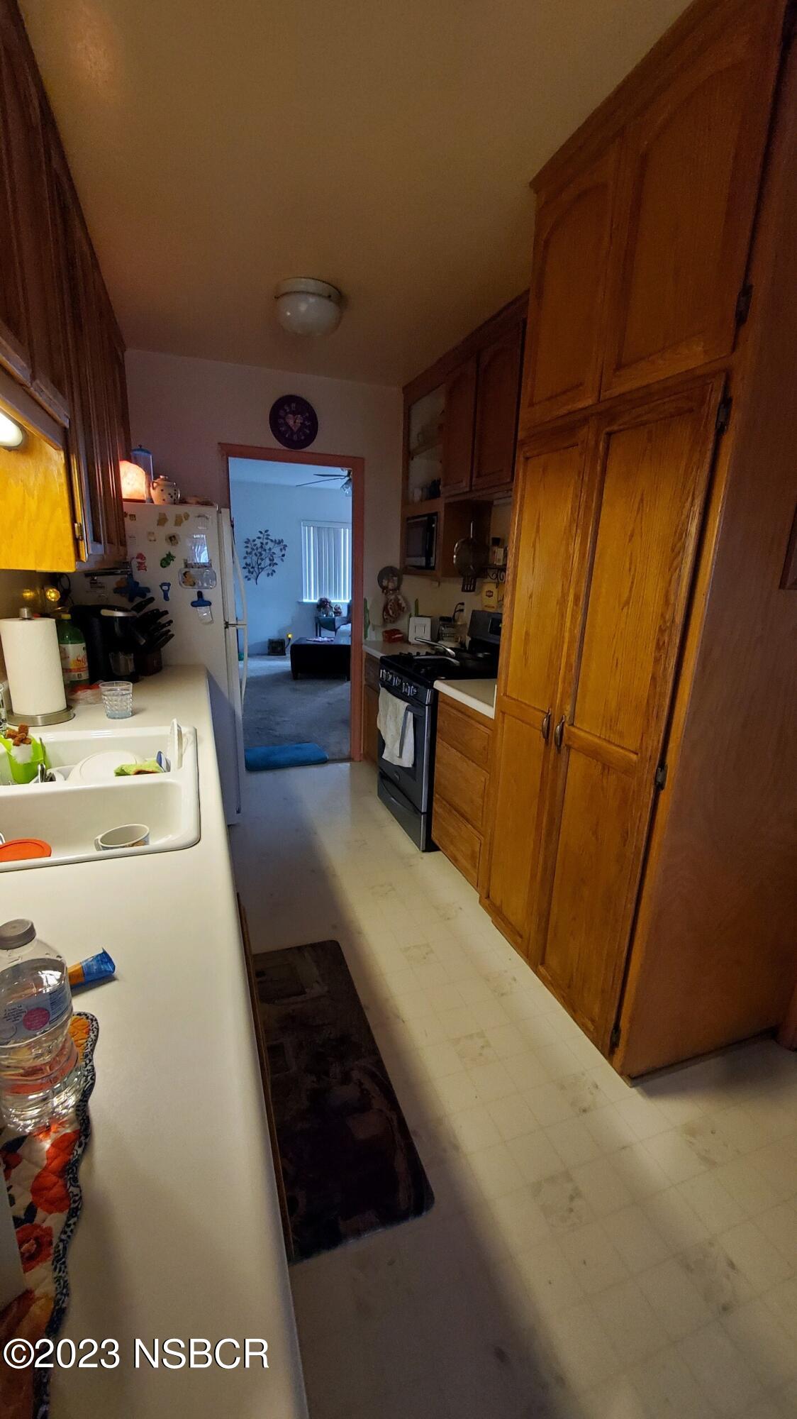 233 South E Street Lompoc, CA 93436 - Photo 8 of 17 a kitchen with stainless steel appliances granite countertop a refrigerator a stove and a sink with wooden cabinets