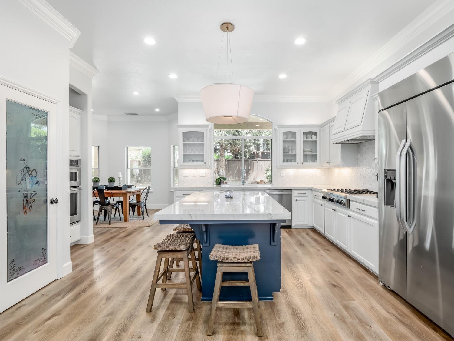 371 West Warwick Avenue Clovis, CA 93619 - Photo 12 of 42 a kitchen with stainless steel appliances granite countertop a stove refrigerator and a dining table with wooden floor