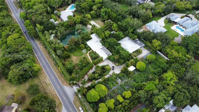an aerial view of residential houses with outdoor space and trees