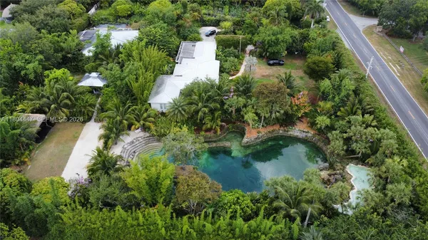 an aerial view of residential house with outdoor space and trees all around
