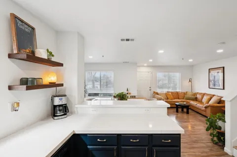 a kitchen with stainless steel appliances granite countertop a sink dishwasher stove and white cabinets with wooden floor