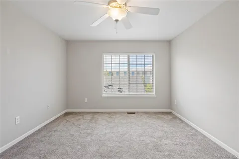 an empty room with a chandelier fan and windows
