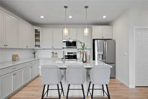 a kitchen with stainless steel appliances a dining table chairs refrigerator and sink