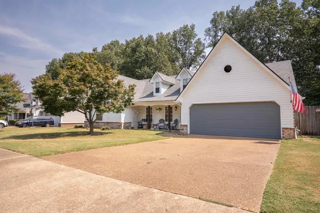 a view of house with yard and trees in the background