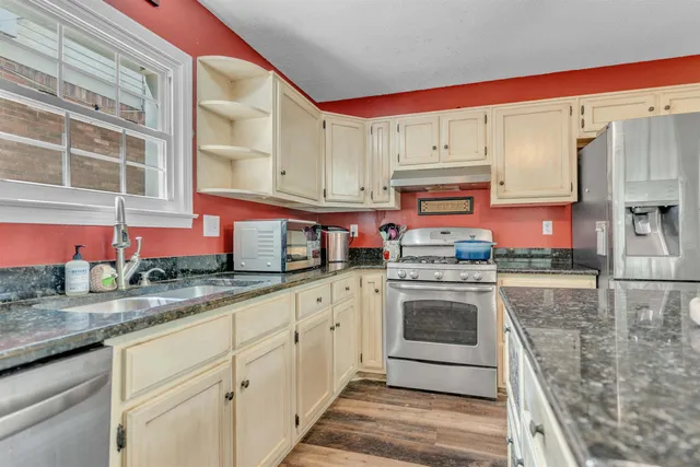 a kitchen with stainless steel appliances granite countertop a stove a sink and a microwave