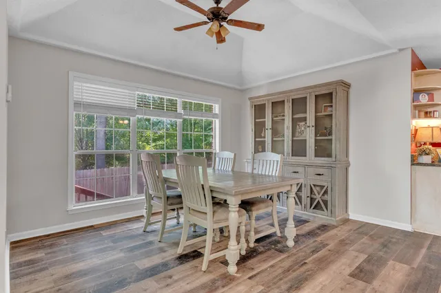 a dining room with furniture window ceiling fan and wooden floor