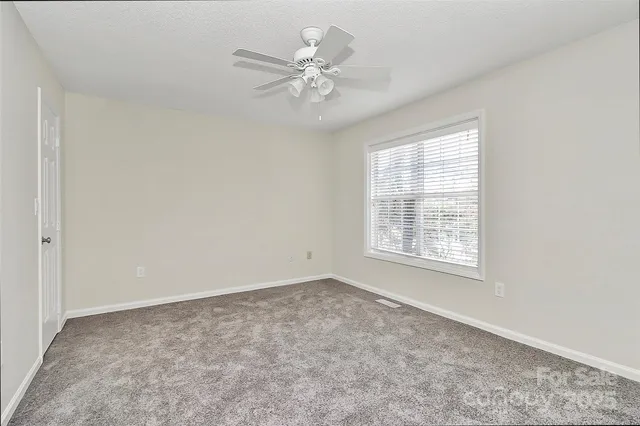 an empty room with a window and a ceiling fan
