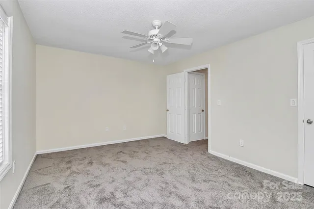 an empty room with a ceiling fan and a window