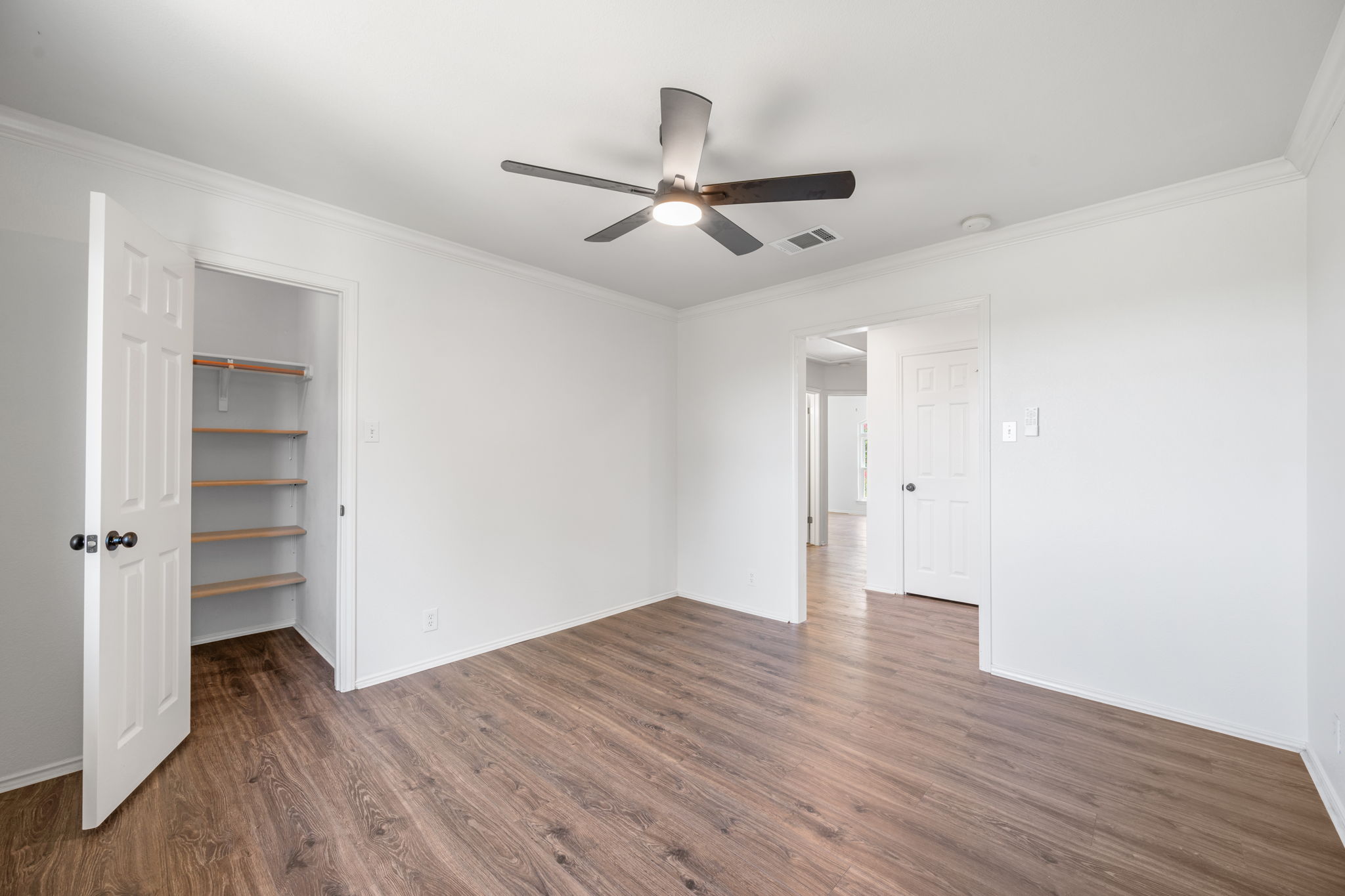 2440 Madeline Loop Cedar Park, TX 78613 - Photo 23 of 33 Unfurnished bedroom featuring crown molding, dark wood-style flooring, a walk in closet, and a ceiling fan