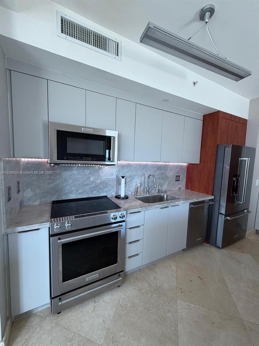 3131 Northeast 188th Street, Unit 1808 Aventura, FL 33180 - Photo 12 of 72 a kitchen with granite countertop a stove and a microwave with cabinets