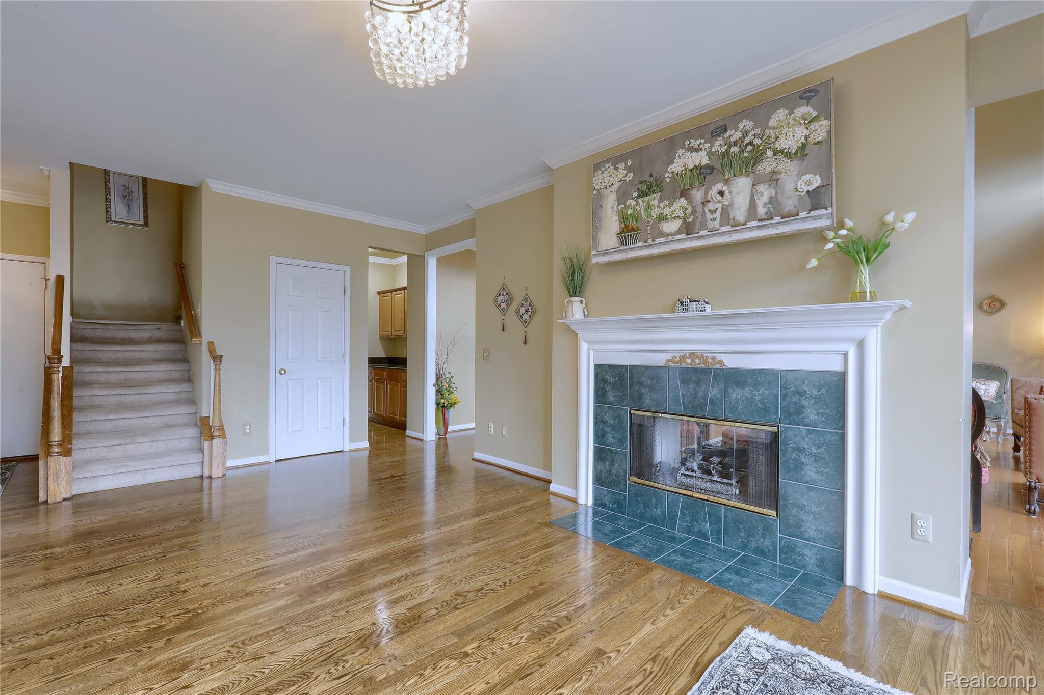 2007 Mapleridge Road Rochester, MI 48309 - Photo 18 of 45 Unfurnished living room featuring crown molding, light wood-style floors, and a tiled fireplace