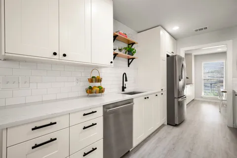 a kitchen with stainless steel appliances white cabinets and wooden floor