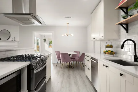 a kitchen with stainless steel appliances a sink a stove cabinets and wooden floor