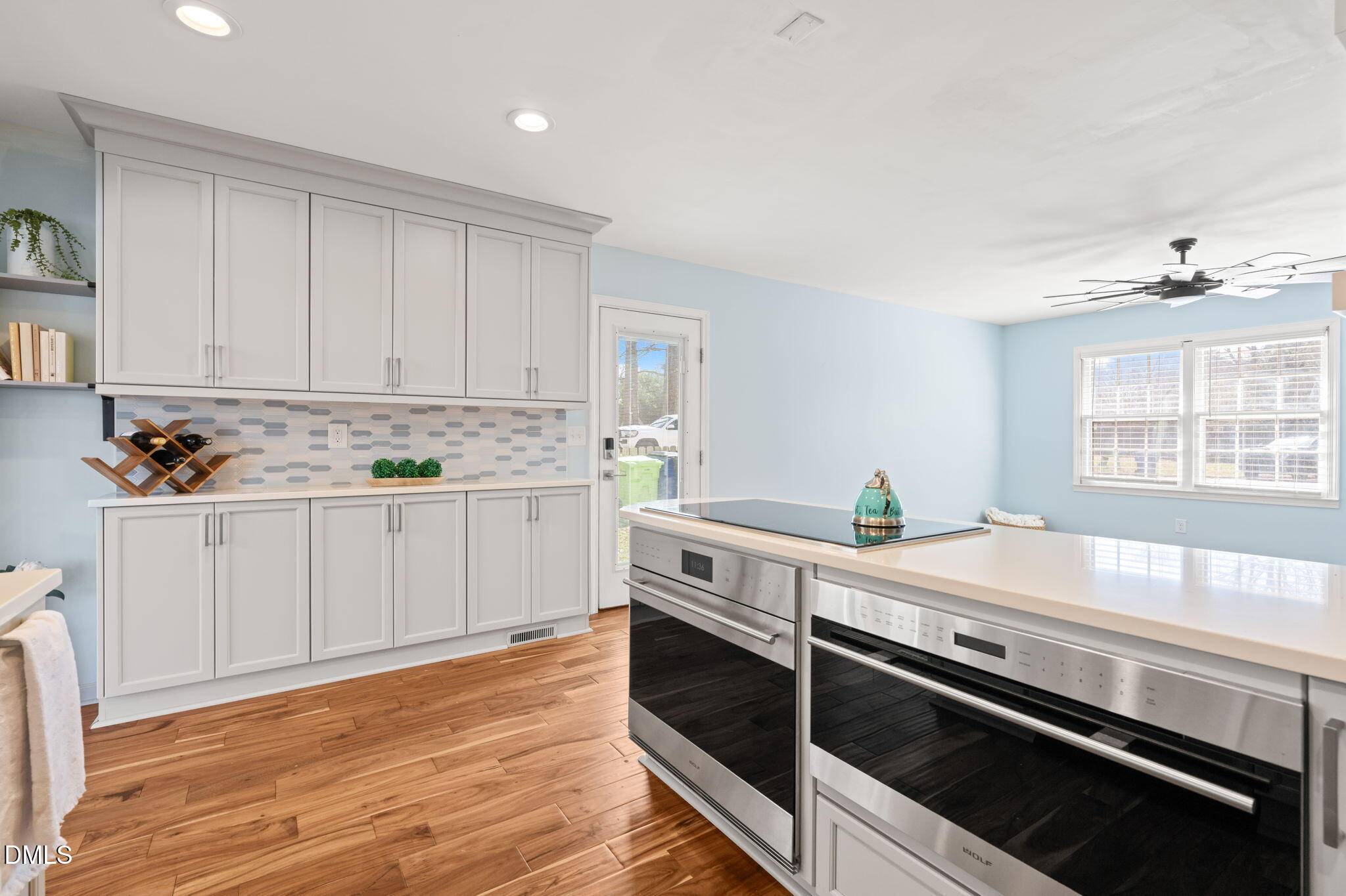 1004 Woodhill Court Raleigh, NC 27615 - Photo 12 of 43 a kitchen with a stove white cabinets wooden floor and a window