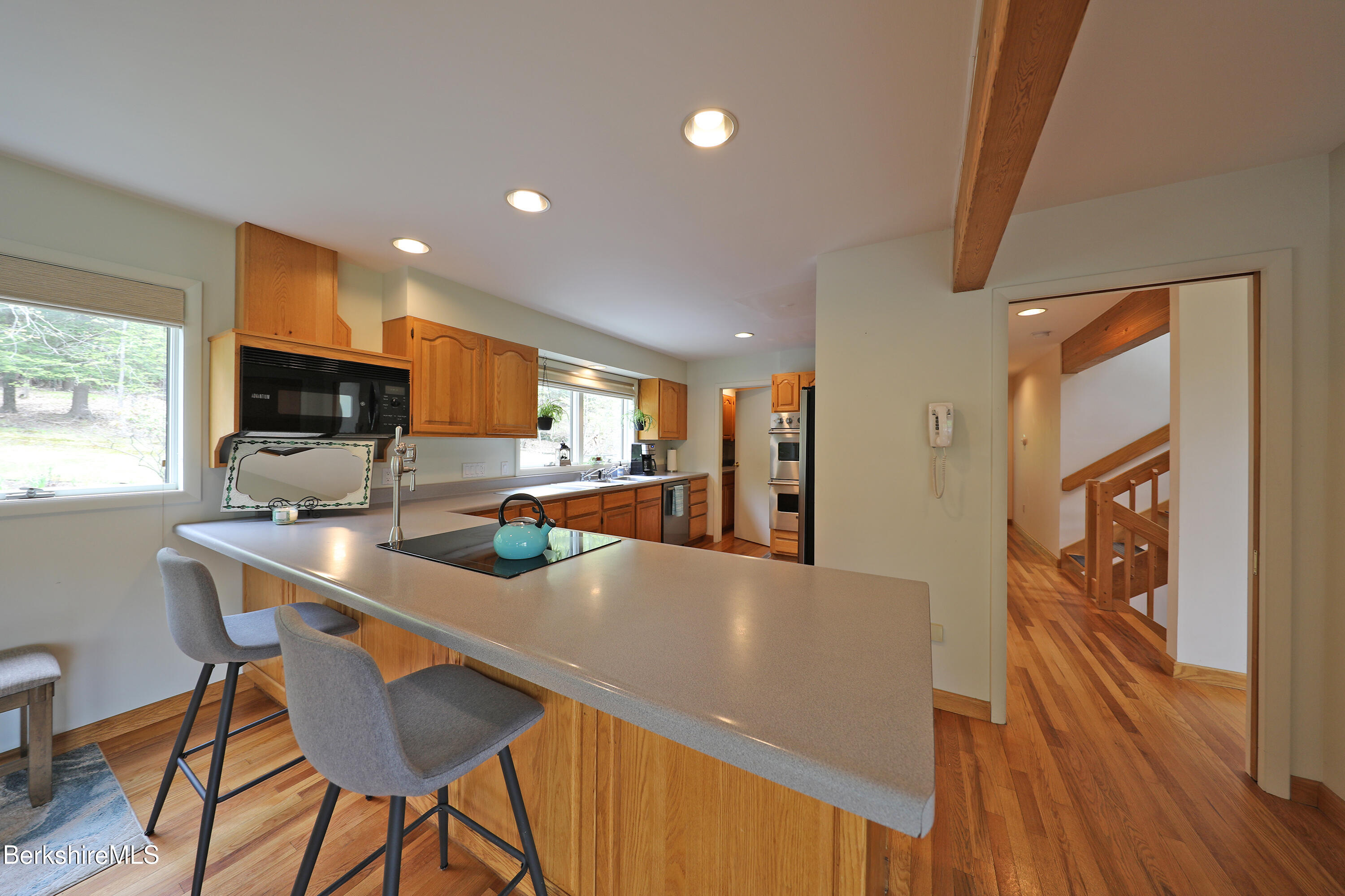 126 Temple Road New Lebanon, NY 12125 - Photo 24 of 37 a kitchen with stainless steel appliances a stove a refrigerator a microwave oven with a dining table and chairs with wooden floor
