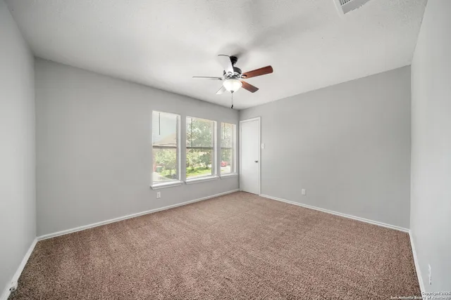 an empty room with windows and ceiling fan