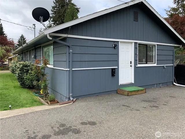 a backyard of a house with plants and barbeque oven
