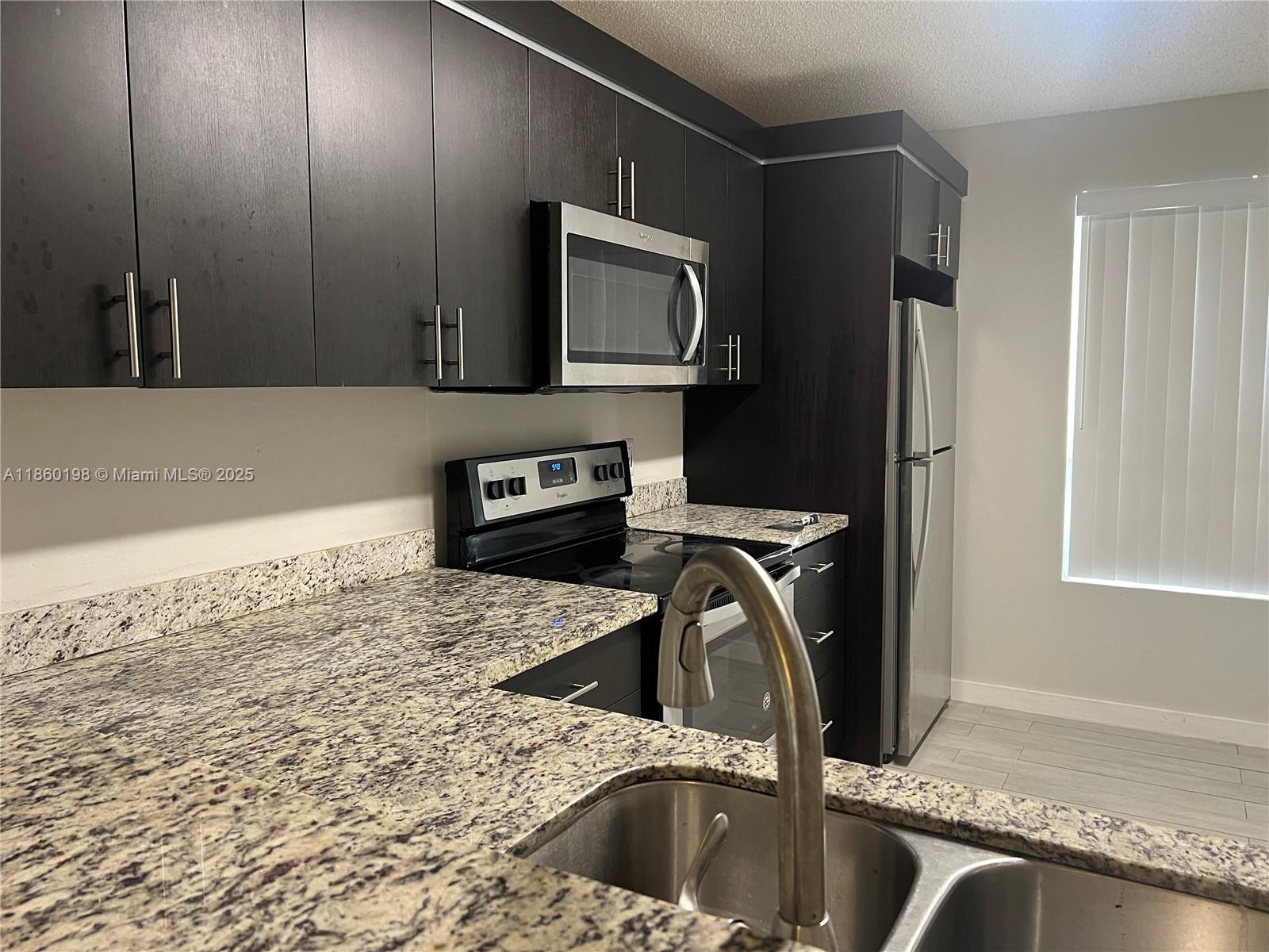 2228 Southwest 80th Terrace, Unit 2228 Miramar, FL 33025 - Photo 1 of 18 a kitchen with a sink a stove and a microwave