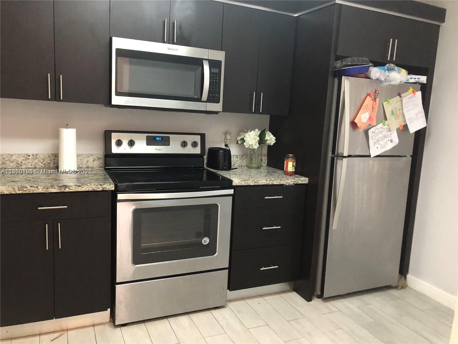 2228 Southwest 80th Terrace, Unit 2228 Miramar, FL 33025 - Photo 2 of 18 a kitchen with stainless steel appliances granite countertop a refrigerator stove and microwave