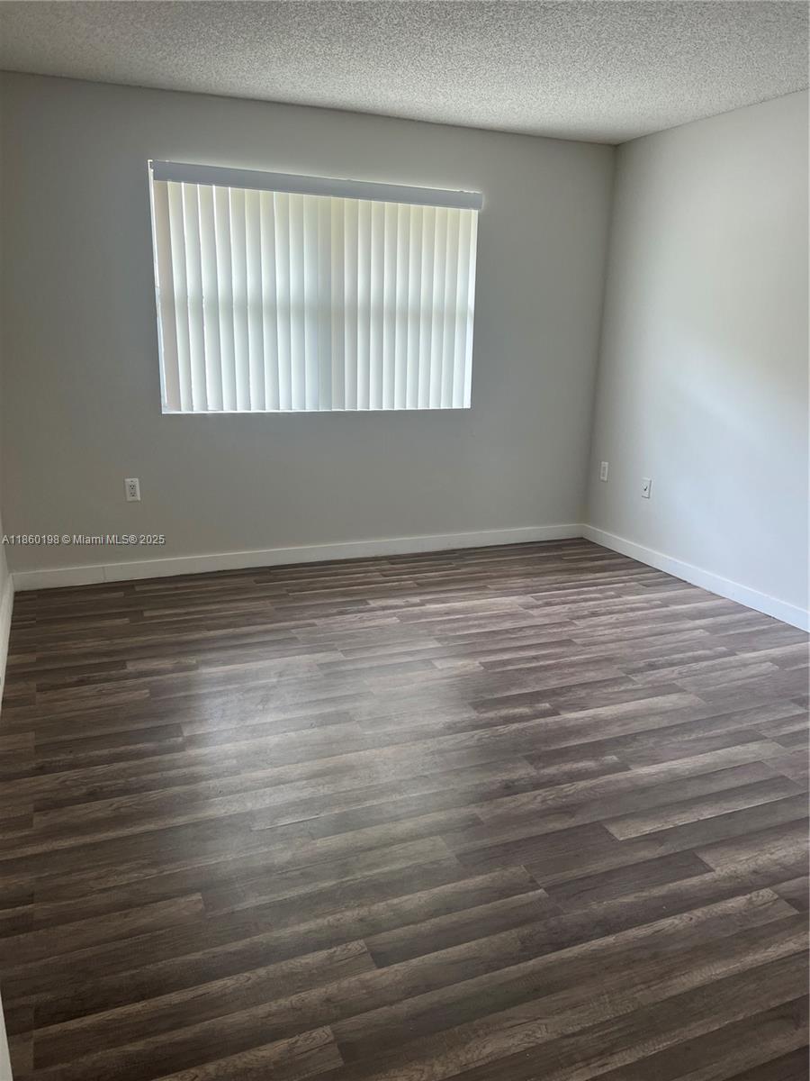 2228 Southwest 80th Terrace, Unit 2228 Miramar, FL 33025 - Photo 8 of 18 a view of an empty room with wooden floor and a window