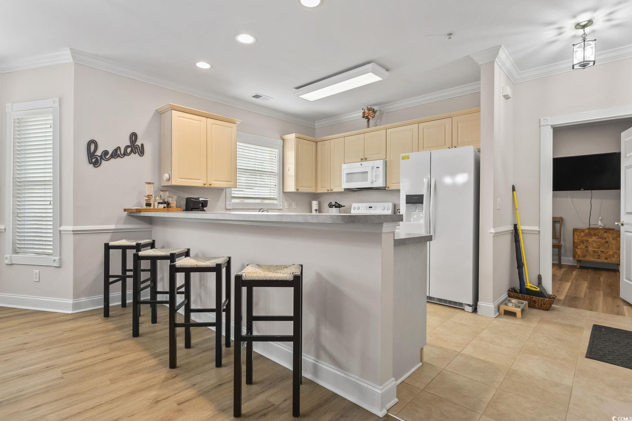 4821 Luster Leaf Circle, Unit 105 Myrtle Beach, SC 29577 - Photo 14 of 40 Kitchen featuring crown molding, white appliances, recessed lighting, a breakfast bar, and a peninsula