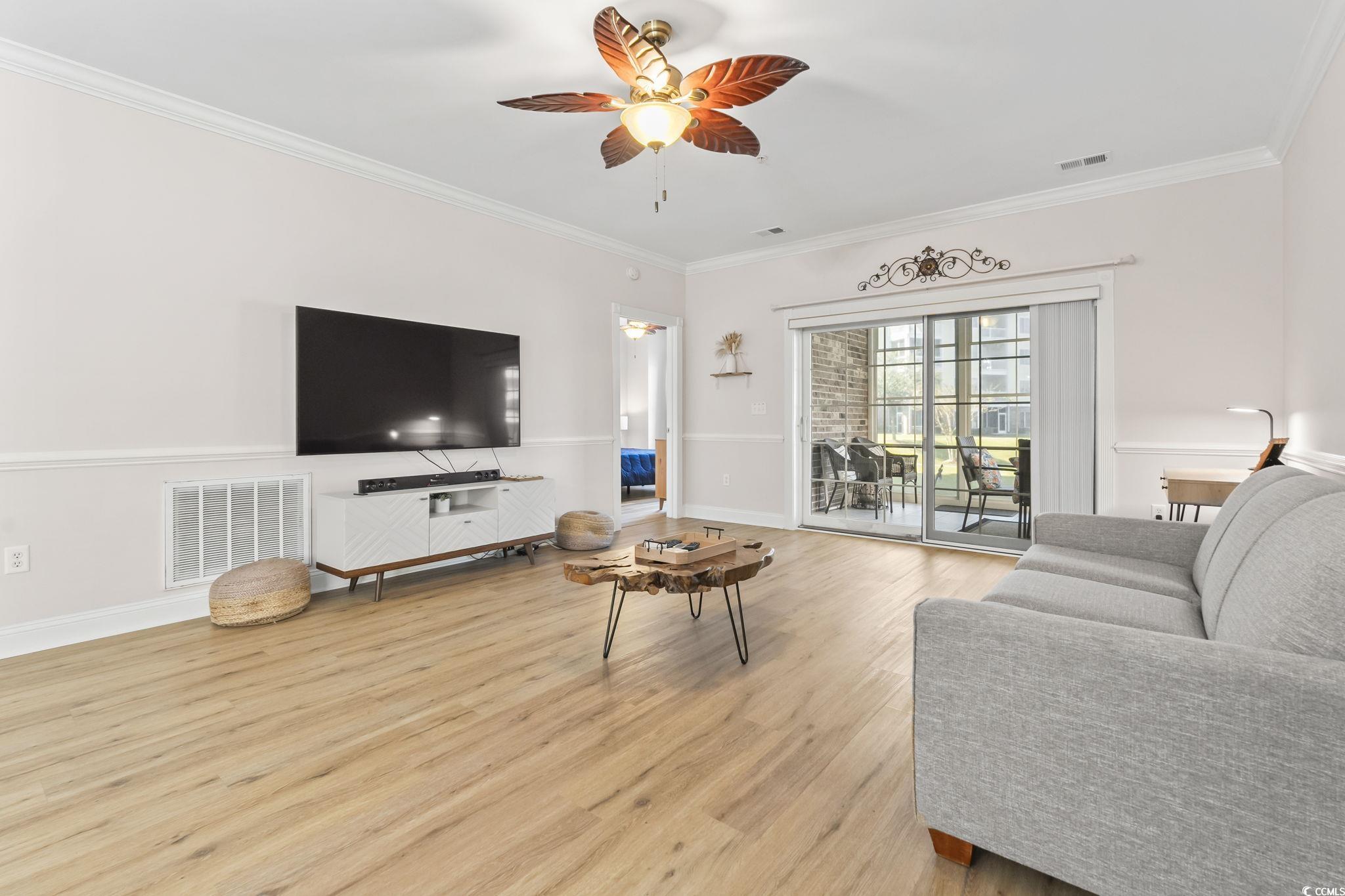4821 Luster Leaf Circle, Unit 105 Myrtle Beach, SC 29577 - Photo 28 of 40 Living area featuring ornamental molding, light wood-style flooring, and a ceiling fan