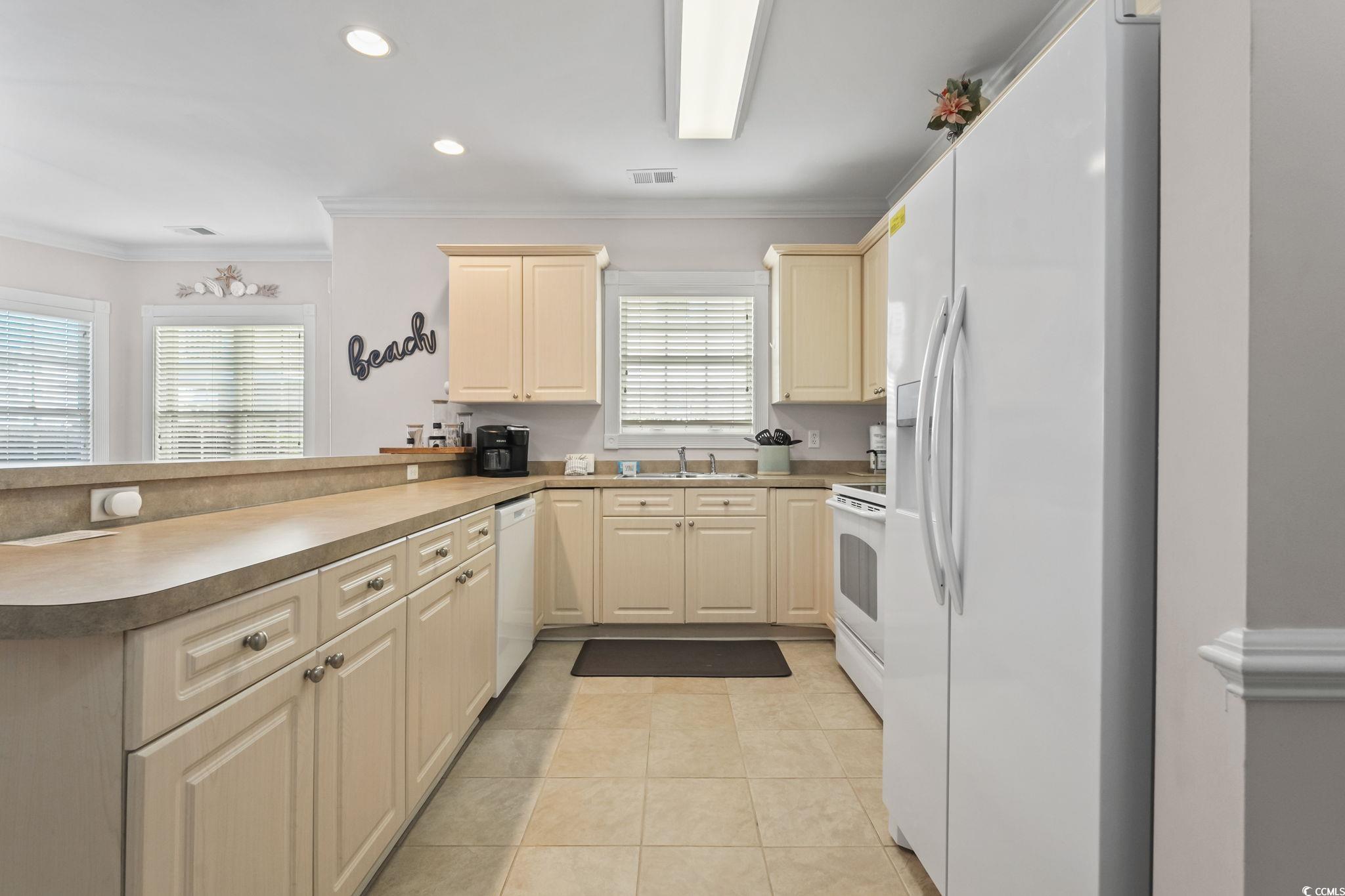 4821 Luster Leaf Circle, Unit 105 Myrtle Beach, SC 29577 - Photo 3 of 40 Kitchen featuring white appliances, crown molding, recessed lighting, light tile patterned floors, and a peninsula