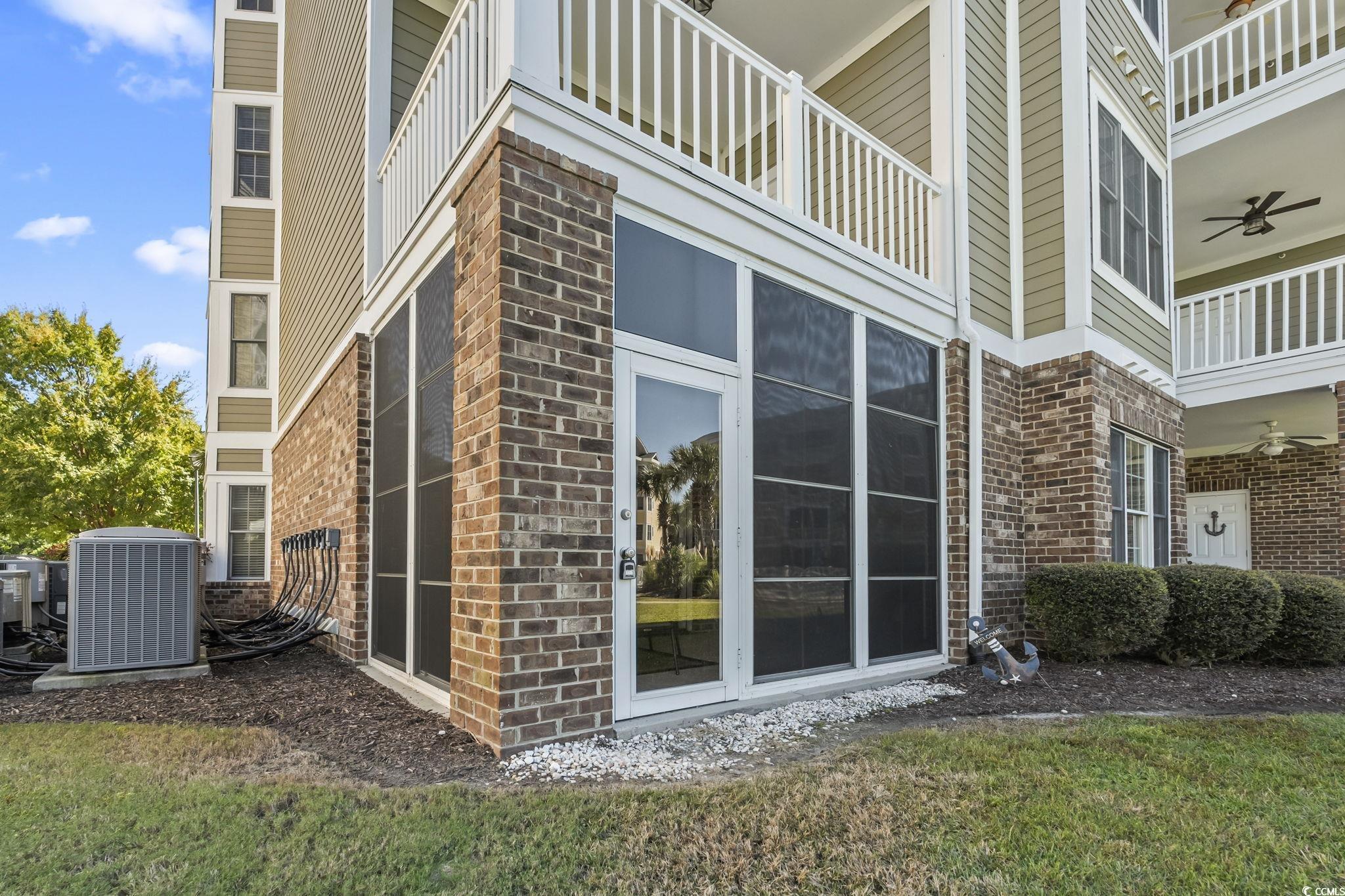 4821 Luster Leaf Circle, Unit 105 Myrtle Beach, SC 29577 - Photo 39 of 40 View of home's exterior featuring a ceiling fan, a balcony, brick siding, and a yard